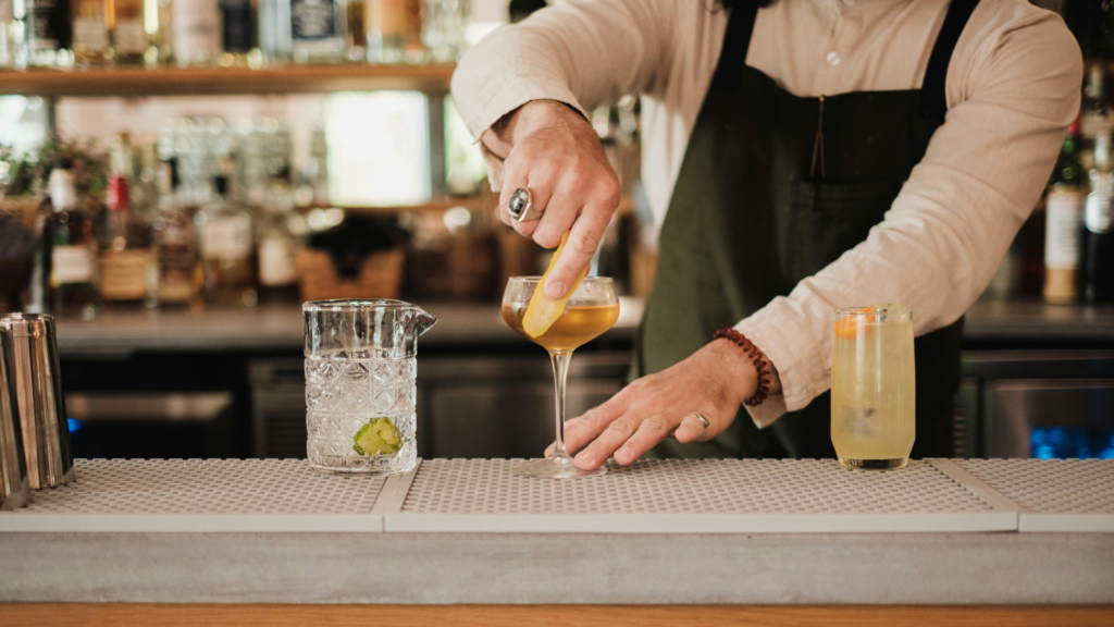 Bartender prepara e decora bebidas frias num bar profissional.
